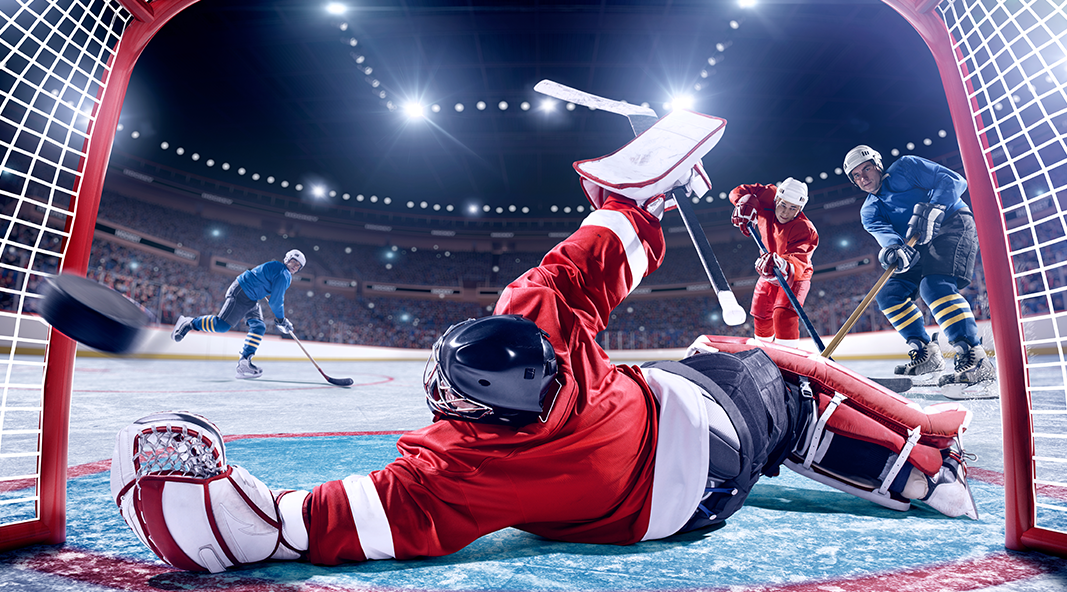 A hockey player slides to defend a goal.