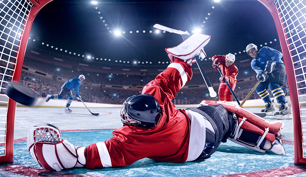 A hockey player slides to defend a goal.